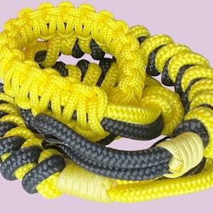 以下が含まれることがあります： 黒と黄色の編み紐で、端には結び目があります。紐は巻き付けられ、ねじられています。