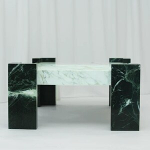 May include: A rectangular marble coffee table with a white and green veined pattern. The table has four dark green legs and a matching tabletop. The legs are rectangular and support the tabletop.