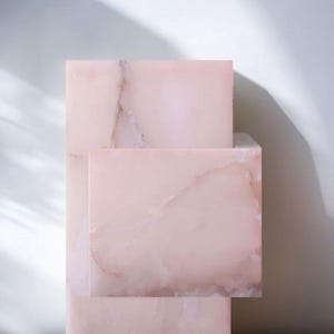 A stack of three pink onyx rectangular table made of marble with white veining.