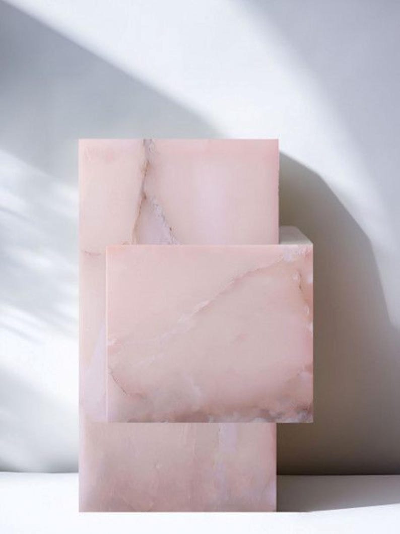 A stack of three pink onyx rectangular table made of marble with white veining.