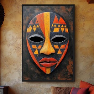 May include: A framed, colorful African mask with a black background. The mask features geometric patterns in orange, yellow, and black, with a prominent orange nose and red lips. The mask is displayed on a textured wall in a room with a curved sofa and decorative pillows.