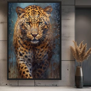 May include: A framed artwork featuring a detailed portrait of a leopard. The leopard has a tan coat with black spots and green eyes. The background has a blue and brown watercolor effect. The artwork is displayed on a gray wall.