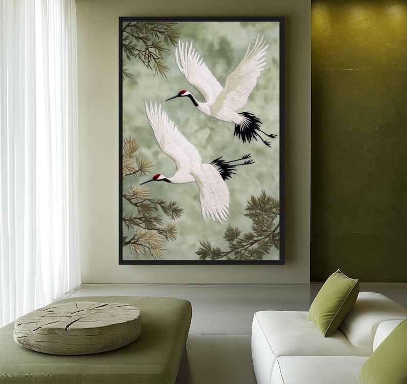 Puede incluir: Una obra de arte enmarcada que presenta dos grullas blancas en vuelo sobre un fondo verde y gris suave. Las grullas tienen marcas negras y rojas, con plumas de ala detalladas. La obra de arte est&aacute; enmarcada en un borde negro, con ramas de &aacute;rboles en las esquinas.