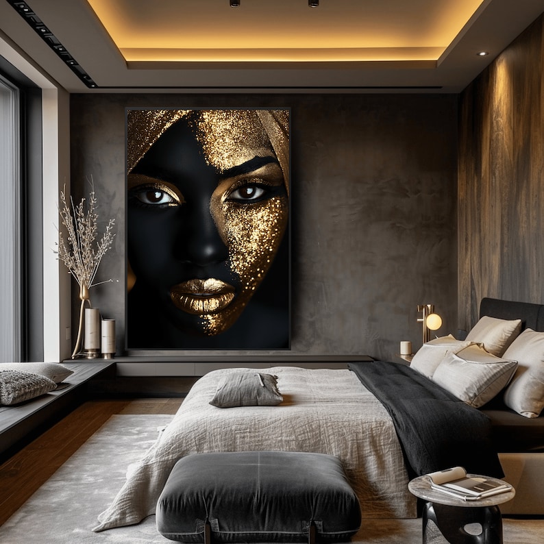 May include: An abstract portrait of a woman's face in black and gold. The woman's face is covered in gold glitter and her lips are painted gold. The portrait is hanging on a wall in a bedroom with a bed and bedside table.