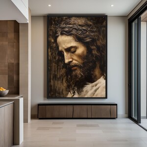 May include: A large framed painting of a man with a crown of thorns and a beard, looking down with his eyes closed. The painting is in a dark, rustic style and is hanging on a wall in a modern home.