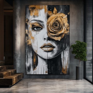 May include: Abstract painting of a woman's face with a large golden rose covering one eye. The painting is done in black, white, and gold paint.