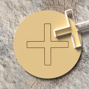 Könnte beinhalten: Ein goldfarbener Kreis mit einem Pluszeichen in der Mitte und einem 3D-Pluszeichen darüber. Das Bild ist vor einem strukturierten, hellen Holzgrund platziert.