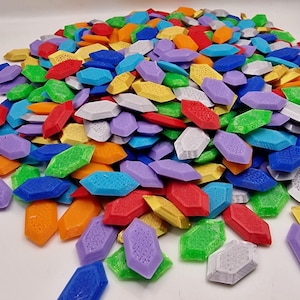 Może przedstawiać: Duża sterta kolorowych, fasetowanych, plastikowych klejnotów. Klejnoty są w różnych odcieniach czerwonego, pomarańczowego, żółtego, zielonego, niebieskiego, fioletowego i srebrnego.