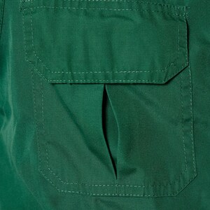 Op de afbeelding: Een donkergroen utility shirt met een grote, gestikte zak aan de voorkant. De zak heeft een klep met een kleine opening aan de bovenkant.