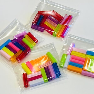 May include: Three clear plastic bags filled with an assortment of cylindrical tube beads in various translucent and opaque colors, including red, blue, yellow, green, pink, orange, and purple, arranged in small stacks within each individual pouch.