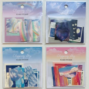 May include: Four packages of colorful flake stickers with the text "Clipping Sky" and "Flake Sticker" on the front. Each package contains different designs of clouds, rainbows, stars, and moons.
