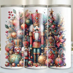 May include: A set of three white tumblers with a Christmas theme. The tumblers feature a nutcracker, a Christmas tree, and ornaments in red, green, gold, and blue.