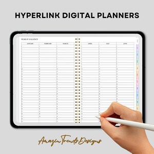 May include: A digital planner with a year at a glance view. The planner is open to show January through June. The planner has a white background with black text and lines. The planner is bound with a gold coil.