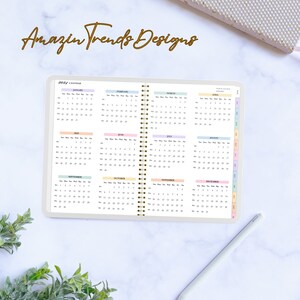 May include: A 2021 calendar with a pastel color scheme. Each month is displayed on a separate page with a different pastel color. The calendar is bound with a gold spiral.