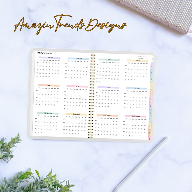 May include: A 2021 calendar with a pastel color scheme. Each month is displayed on a separate page with a different pastel color. The calendar is bound with a gold spiral.