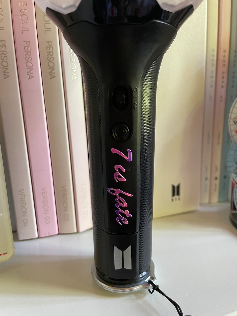Peut inclure: Un b&acirc;ton lumineux noir avec une base argent&eacute;e et une sangle noire. Le b&acirc;ton lumineux a un bouton argent&eacute; et un autocollant rose et violet qui dit "7 es fate".