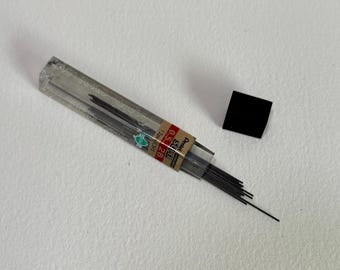 May include: A clear plastic container filled with 2B lead refills for mechanical pencils. The container has a label that reads "Super 0.5 2B 12 Pcs."