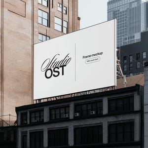 Może przedstawiać: Biały billboard z tekstem "Studio OST" i "Frame mockup with smart layer" w kolorze czarnym. Billboard jest zamontowany na budynku w mieście.