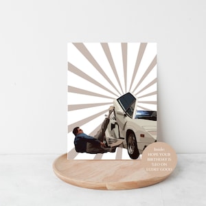May include: A birthday card with a white sports car and a person leaning against it, set against a beige radial background. The card reads: "Inside: HOPE YOUR BIRTHDAY IS 'LEO ON LUDES' GOOD."