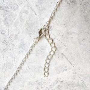 May include: Silver chain necklace with a lobster clasp closure. The chain is made of small, linked circles.