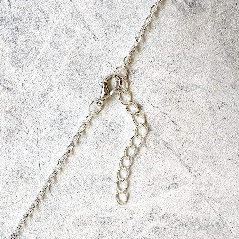 May include: Silver chain necklace with a lobster clasp closure. The chain is made of small, linked circles.