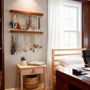 May include: A bedroom scene featuring a wooden jewelry organiser with various necklaces. A small wooden bedside table with a drawer and a woven basket sits below. A bed and desk are also visible.
