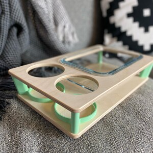 May include: A wooden serving tray with a natural finish and mint green accents. The tray features a rectangular glass dish, two circular cutouts, and two recessed areas for holding items. The tray is designed for convenience and style.