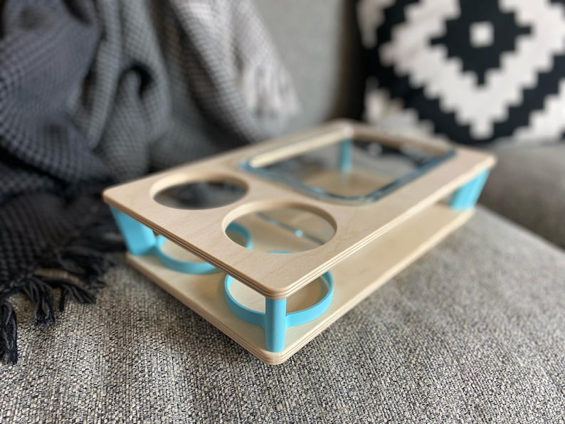 May include: A wooden serving tray with a light blue trim and accents. The tray has cutouts for two glasses, a square dish, and a round dish. The tray is made of light-colored wood and is designed to hold drinks and snacks.