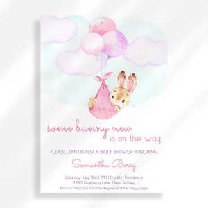 Op de afbeelding: Een babyborrel uitnodiging met een aquarel illustratie van een roze konijn dat roze en paarse ballonnen vasthoudt. De tekst luidt "some bunny new is on the way".