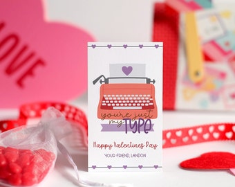Könnte beinhalten: Eine Valentinstagskarte mit einer roten Schreibmaschine und dem Text "you're just my type". Die Karte hat ein violettes Band und den Text "Happy Valentine's Day" und "Your Friend, Landon".