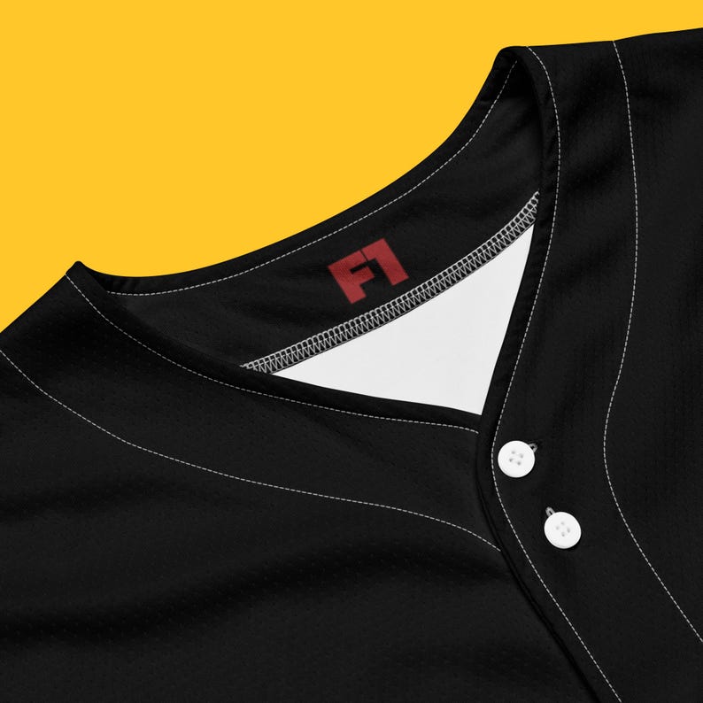 May include: Black baseball jersey with a white v-neck and a red "F1" logo on the collar.