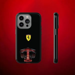 May include: Black iPhone case featuring a Ferrari logo and a red racing car graphic. The case has a black camera bump with three lenses.