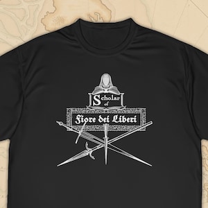 May include: Black t-shirt with a white graphic design featuring a sword and the text "Scholar of Fiore dei Liberi".