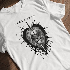 May include: White t-shirt with a black and white graphic of a lion wearing a crown, surrounded by swords and a heart. The text "ardimento" is printed above the graphic.