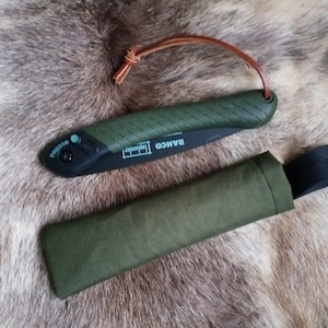 May include: A green folding saw with a black handle and a brown leather strap. The saw is labeled "BAHCO" and "Legend" and has a "Press-Stop" button. The saw is in a green canvas sheath with a black strap.