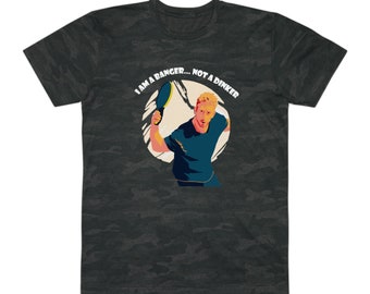May include: A black t-shirt with a camouflage pattern featuring a cartoon illustration of a person playing paddle tennis. The text "I AM A BANGER... NOT A DINKER" is printed in white on the shirt.