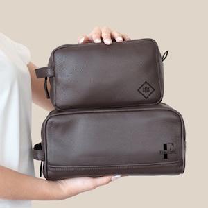 May include: Two brown leather travel bags with zipper closures. The top bag has the initials "CDS" embossed on the front. The bottom bag has the letter "F" and the word "FERGUSON" embossed on the front.