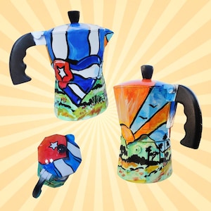 以下が含まれることがあります： 手描きのカラフルなエスプレッソメーカー3台。キューバの国旗のモチーフと、青、赤、オレンジ、緑の色合いの風景が描かれています。各メーカーには黒いハンドルとノブが付いています。