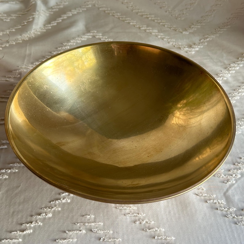 May include: A large, round, brass bowl with a smooth, shiny surface.