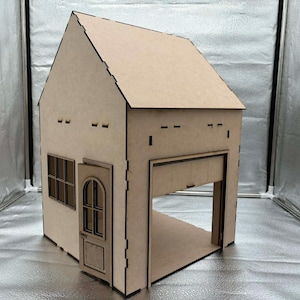 Puede incluir: Una maqueta de casa de madera clara con puerta de garaje, puerta principal y ventana. La casa tiene un tejado a dos aguas. La puerta del garaje está abierta, revelando el interior. La puerta principal está entreabierta.