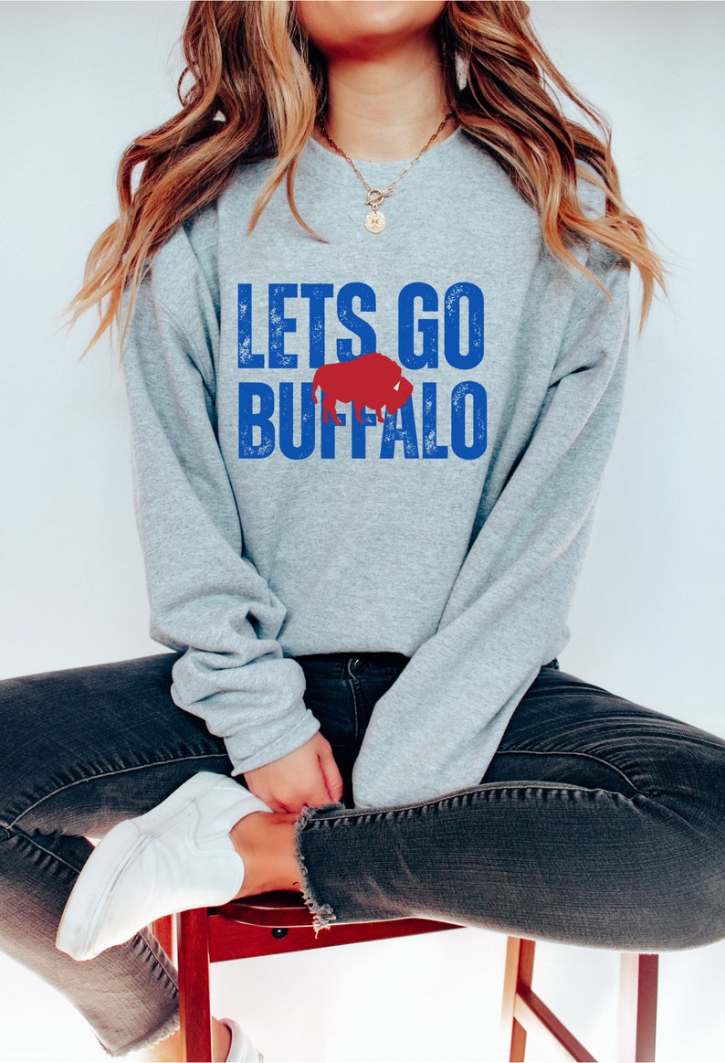 May include: A gray sweatshirt with the text "LETS GO BUFFALO" in blue with a red buffalo silhouette.