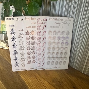 Puede incluir: Cuatro tarjetas blancas con contornos negros de iconos navideños. Las tarjetas están etiquetadas "cada icono = £" y "total = £". Los iconos incluyen un adorno navideño, un hombre de jengibre, una bola de discoteca, una caja de regalo y un bastón de caramelo.