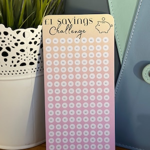 May include: A pink and orange gradient card with a piggy bank icon and the text "£1 savings challenge". The card has 150 circles with the number "£1" written inside each circle. The text "= £150" and "ML Designs" are at the bottom of the card.