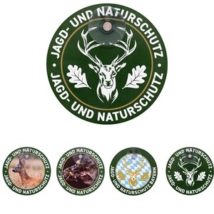 Könnte beinhalten: Eine Sammlung grüner runder Aufkleber mit dem Text "JAGD- UND NATURSCHUTZ" und Wildtierbildern. Der Hauptaufkleber zeigt einen Hirschkopf und Eichenblätter. Zusätzliche Aufkleber zeigen einen Hirsch, ein Pferd und einen Hirsch mit bayerischem Muster.