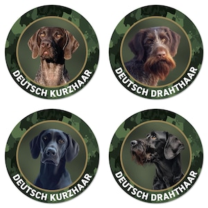 Könnte beinhalten: Vier runde Aufkleber mit Hundeporträts. Zwei Aufkleber zeigen einen braunen Hund mit dem Text "DEUTSCH KURZHAAR". Die anderen beiden zeigen einen schwarzen Hund mit dem Text "DEUTSCH DRAHTHAAR". Jeder Aufkleber hat einen grünen Tarnhintergrund.