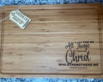 Puede incluir: Una tabla de cortar de madera con un mensaje grabado con láser: "All Things Through Christ Who Strengthens Me Philippians 4:13".