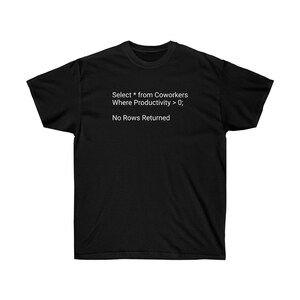 May include: Black t-shirt with white text. The text reads: "Select * from Coworkers Where Productivity > 0; No Rows Returned". The shirt has a crew neck and short sleeves. The fabric appears to be a soft, comfortable material.