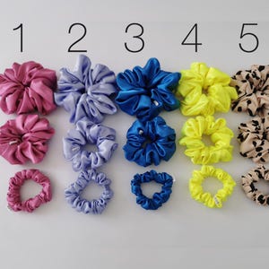 May include: Three rows of colourful scrunchies in different sizes, labelled L, M, and S. The scrunchies are in pink, purple, blue, yellow, and brown with a leopard print.