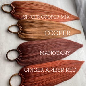 Könnte beinhalten: Vier Haarverlängerungen in Rot- und Brauntönen, jede mit einem braunen Gummiband befestigt. Die Farben sind beschriftet: Ginger Cooper Mix, Cooper, Mahogany und Ginger Amber Red. Die Extensions sind auf einer hellgrauen Oberfläche angeordnet.