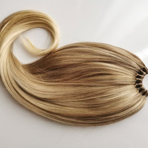 Könnte beinhalten: Eine lange, blonde Pferdeschwanz-Haarverlängerung mit einem braunen Gummiband.